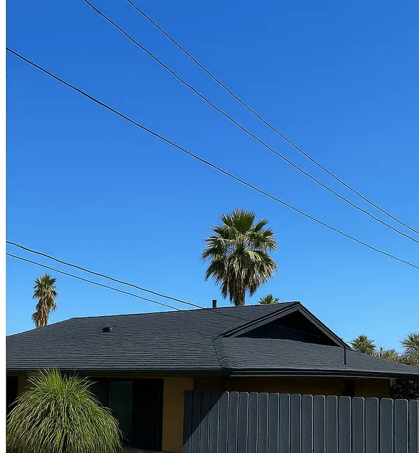 The same home after reroofing, seen from the street: new charcoal shingles and a dark repainted fence
